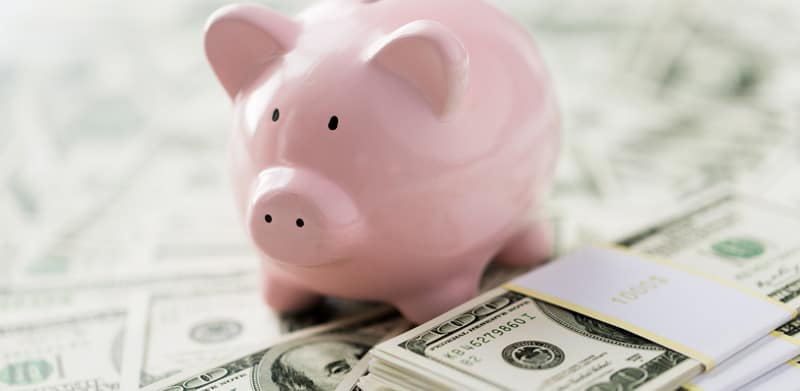 Piggy bank standing on top of piles of money
