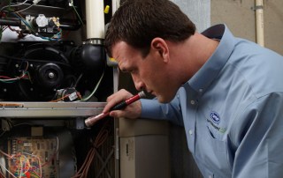 A repairman working on a furnace tune-up in Milwaukee & nearby areas