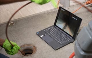 Professional sewer camera inspection detecting blockages in a residential drain system, displayed on a laptop screen.